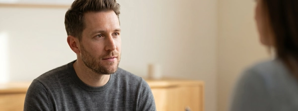 A man participating in a
        professional mental health evaluation with a psychologist, representing clinical clarity for adults experiencing
        prolonged anxiety, depression, or workplace burnout.